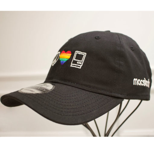 Macstock Hat Pride - 3/4 View - Peace Love Mac logo in white. Heart in rainbow colors. Macstock in white on side panel.